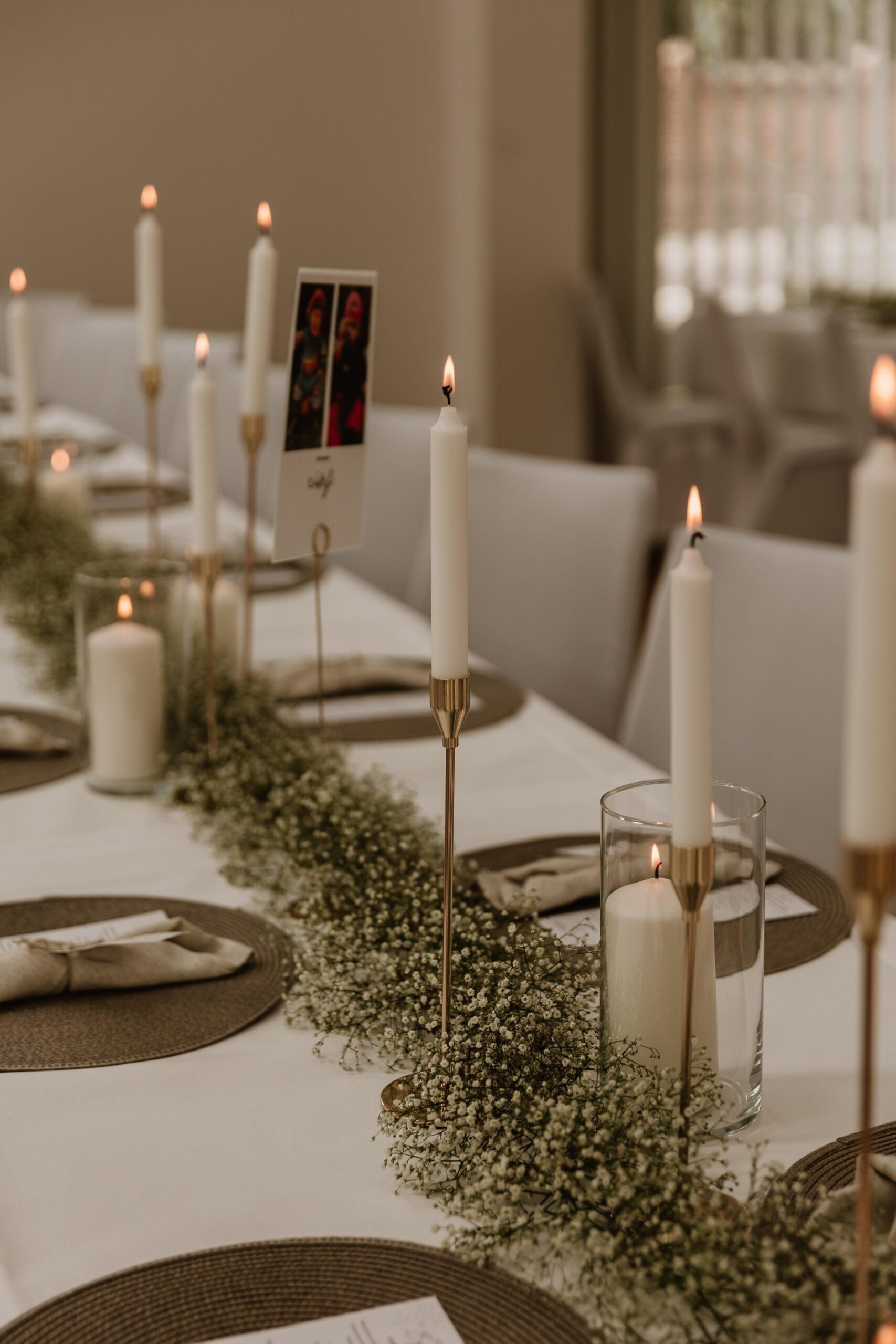 Festlich gedeckte Hochzeitstafel mit Schleierkraut, weißen Kerzen und goldenen Kerzenständern.