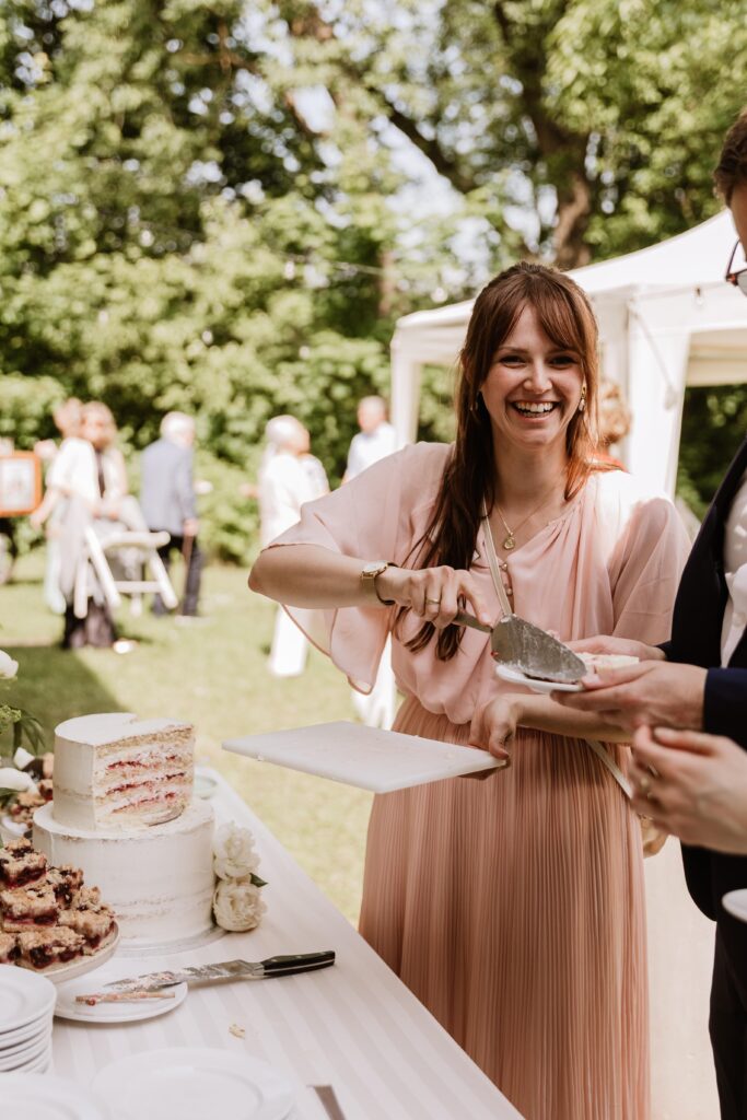Hochzeitsplanerin Romina Blume lacht in die Kamera, während sie Kuchen verteilt.
