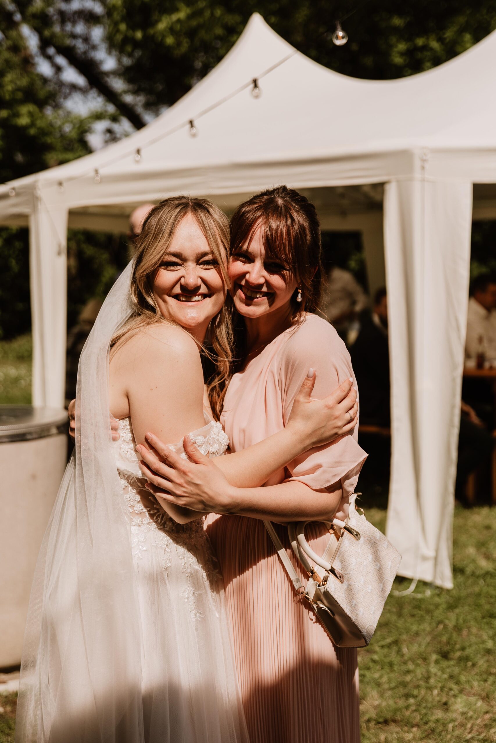 Hochzeitsplanerin und Braut umarmen sich lachend während der Feier.