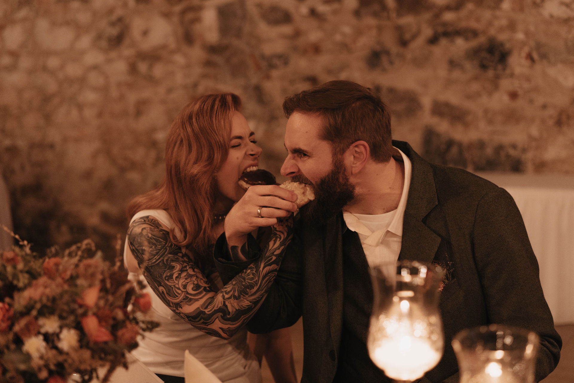Ein authentischer Moment bei einer Scheunenhochzeit in Brandenburg mit einem Brautpaar beim Tortenanschnitt mit Donuts.
