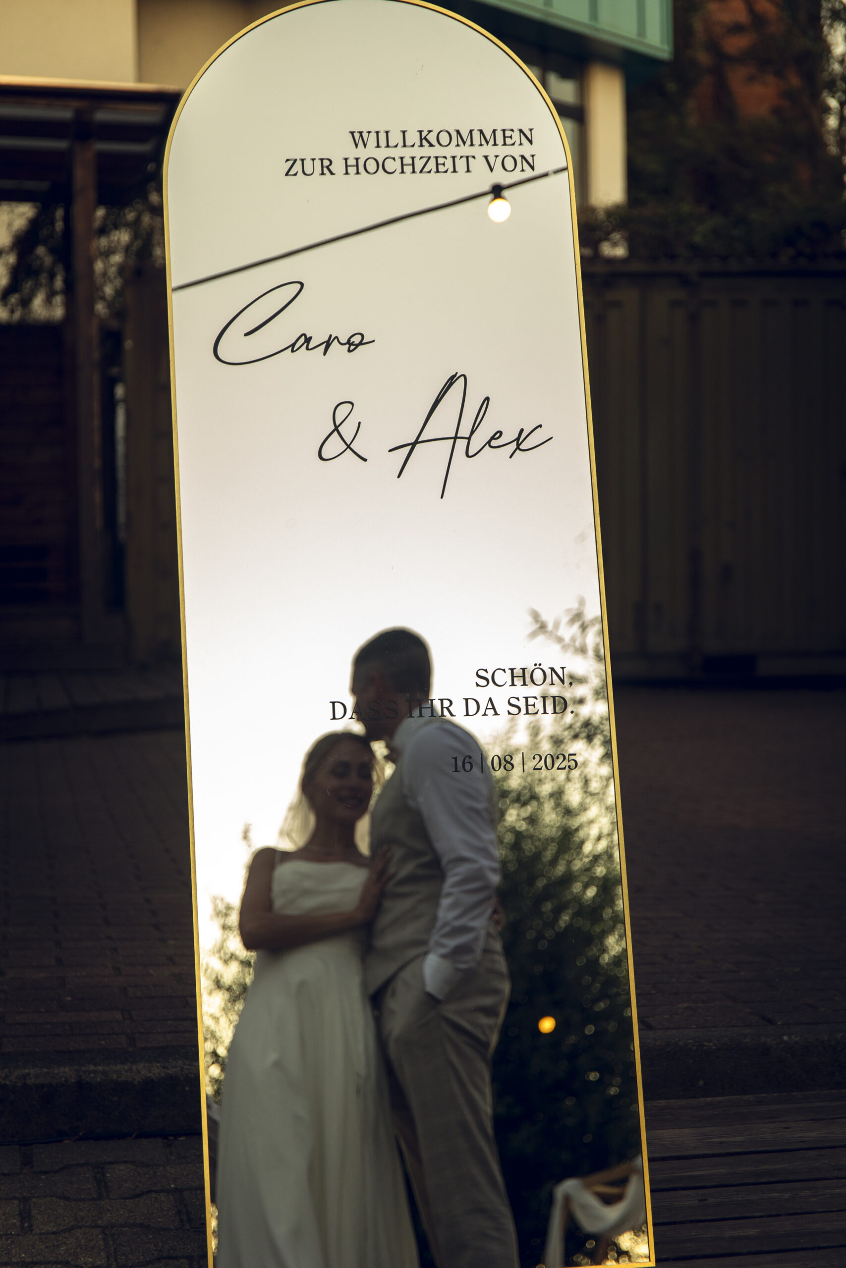 Eleganter Spiegel mit Goldrahmen als Willkommensschild am Abend bei Sonnenuntergang.