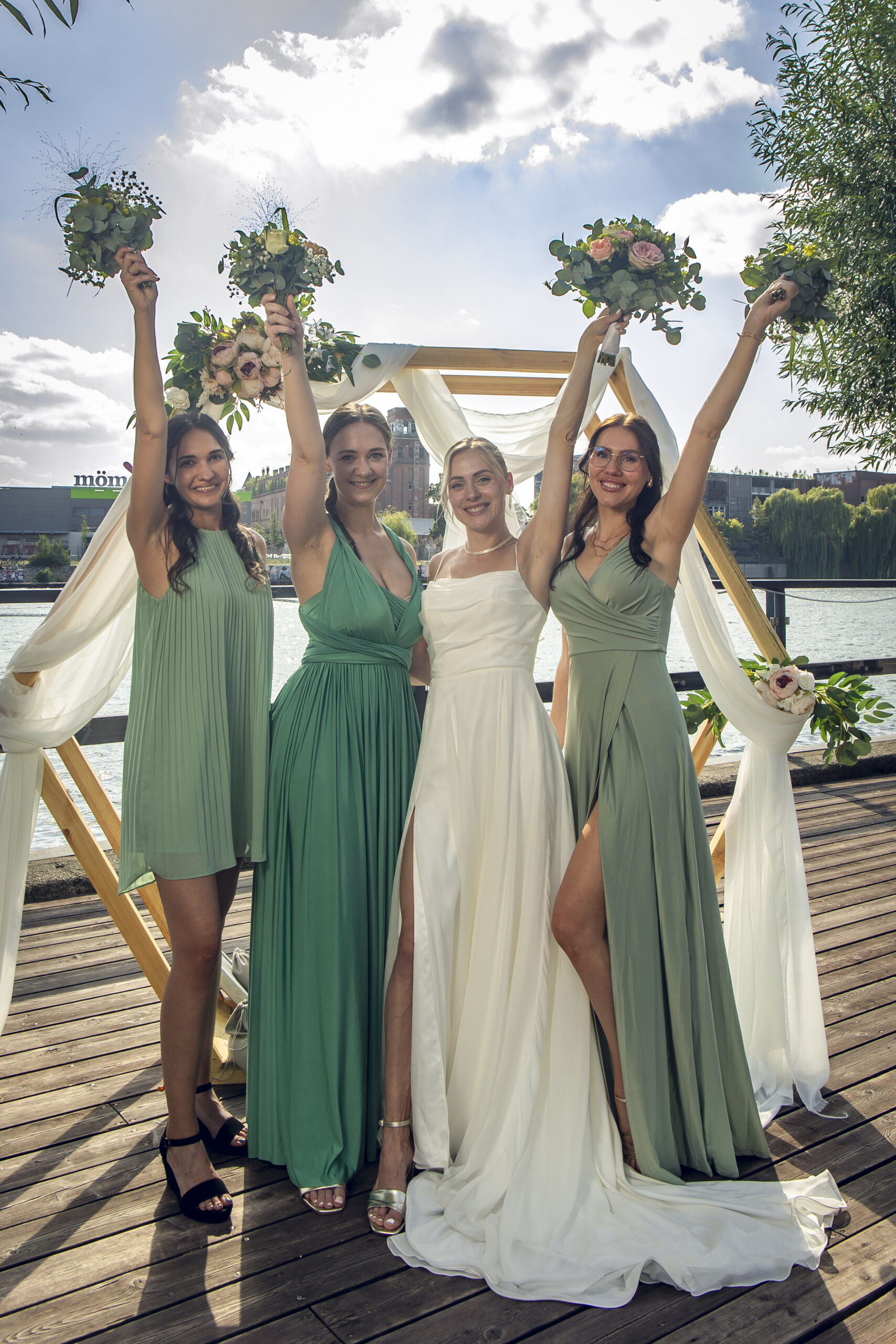 Braut feiert ausgelassen mit ihren Brautjungfern und ihrer Trauzeugin im Freien während der Hochzeit.