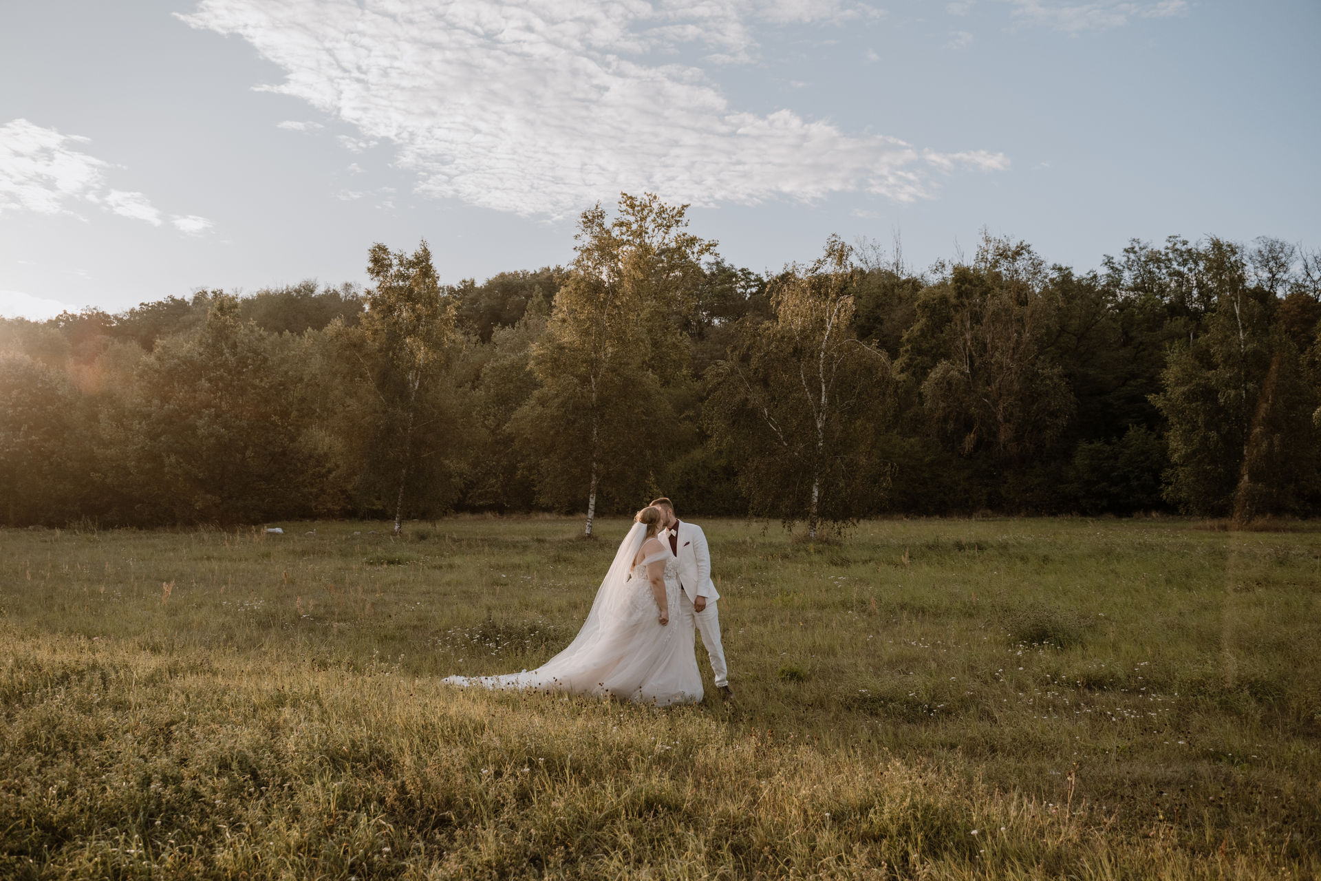 Brautpaar bei einer sommerlichen Landhochzeit in Brandenburg auf einer Wiese im Abendlicht